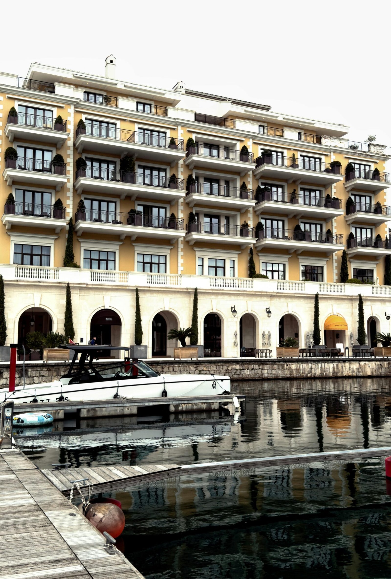 Elegant hotel by marina with docked yacht reflecting luxury travel.